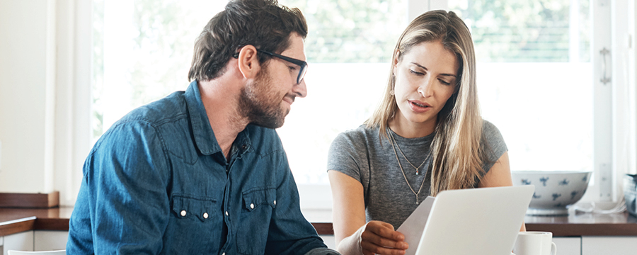 Middle-aged couple at kitchen table, reviewing finances.