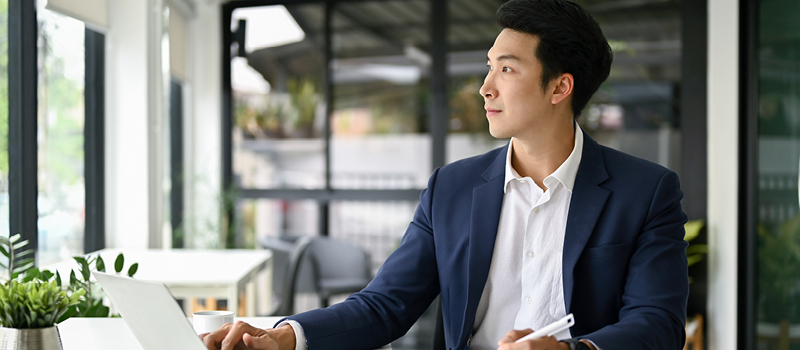 Businessman at his office desk looking out the window with a thoughtful expression
