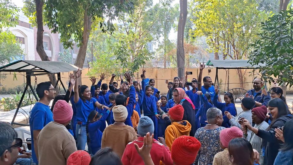 A large group of people wearing matching blue shirts gather outdoors in a courtyard