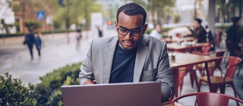 Smiling man reviewing his accounts at an open air cafe.
